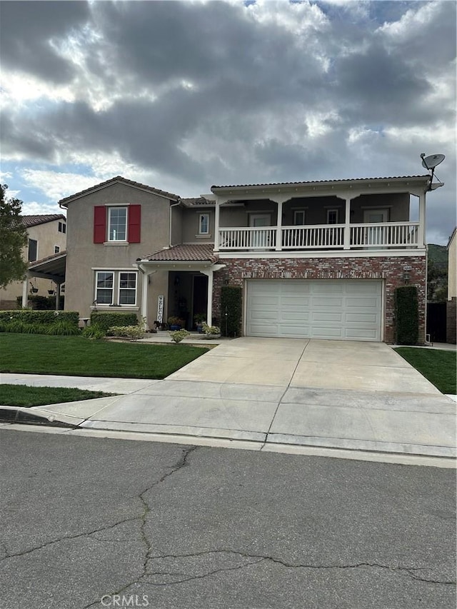 traditional home featuring driveway, a balcony, a front lawn, an attached garage, and stucco siding