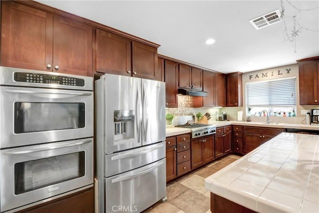 34440 Fawn Ridge Pl, Yucaipa, CA 92399 - kitchen featuring stainless steel appliances, tile countertops, light tile patterned floors, a sink, and backsplash