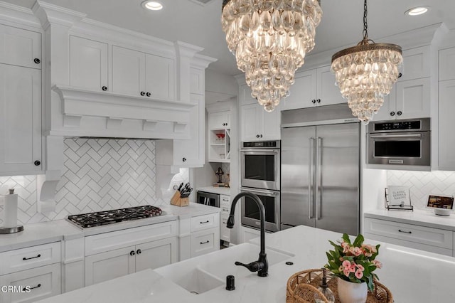 20752 Veneto Way, Porter Ranch, CA 91326 - kitchen with stainless steel appliances, a chandelier, decorative backsplash, white cabinetry, and light countertops