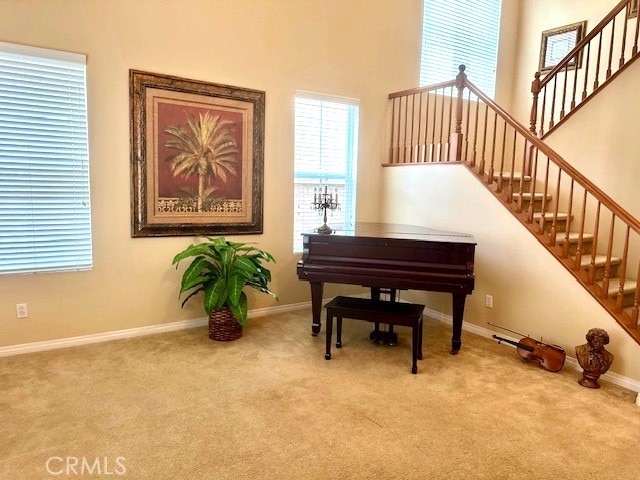 sitting room with carpet floors, baseboards, and stairway