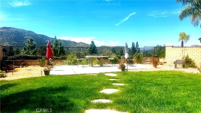 view of yard with a patio, fence, and a mountain view