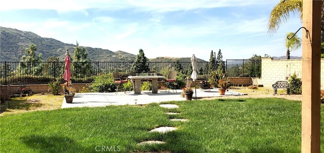 view of yard with fence, a mountain view, and a patio area
