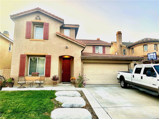 mediterranean / spanish-style house featuring a tile roof, a front lawn, concrete driveway, an attached garage, and stucco siding