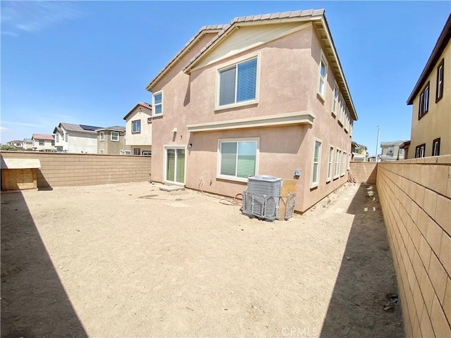 rear view of house with a fenced backyard, stucco siding, and cooling unit