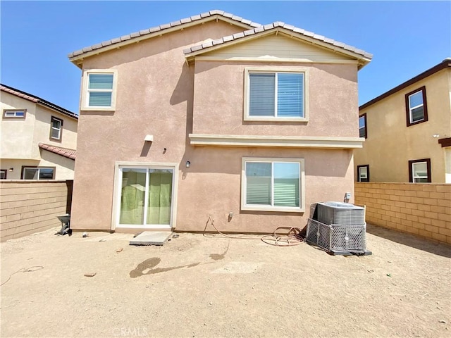 rear view of house featuring cooling unit, stucco siding, and a fenced backyard