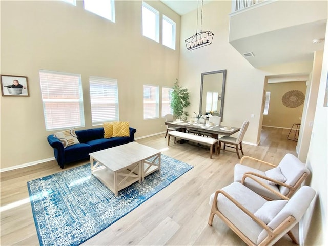 living room with baseboards, visible vents, wood finished floors, and a high ceiling