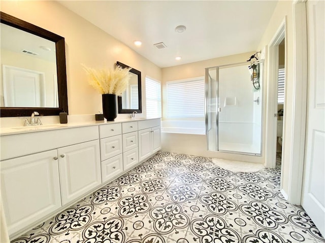 bathroom featuring visible vents, a stall shower, double vanity, and a sink