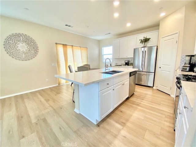 kitchen featuring appliances with stainless steel finishes, visible vents, backsplash, and a sink