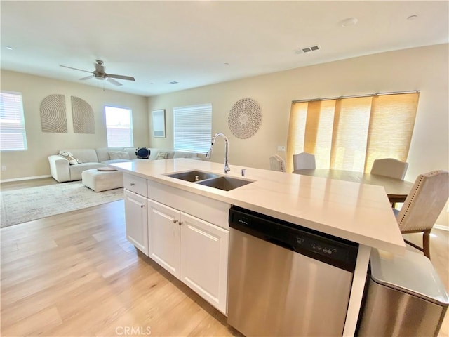 kitchen featuring white cabinetry, stainless steel dishwasher, a sink, light wood finished floors, and a ceiling fan