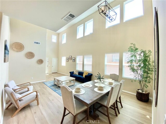 12952 Claremore St, Victorville, CA 92392 - dining space featuring light wood finished floors, a high ceiling, and a chandelier