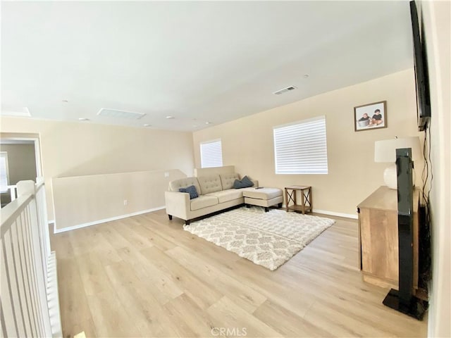 living area with light wood finished floors, visible vents, and baseboards