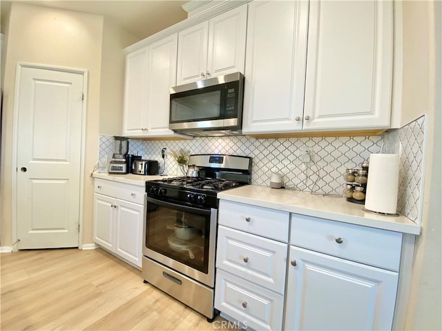 kitchen with decorative backsplash, light wood-style flooring, white cabinets, stainless steel appliances, and light countertops