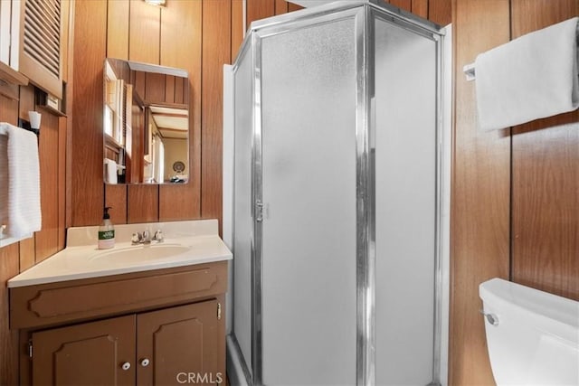 bathroom featuring toilet, a stall shower, and vanity