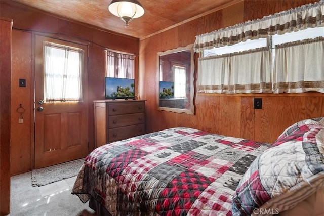 carpeted bedroom featuring multiple windows and wood walls