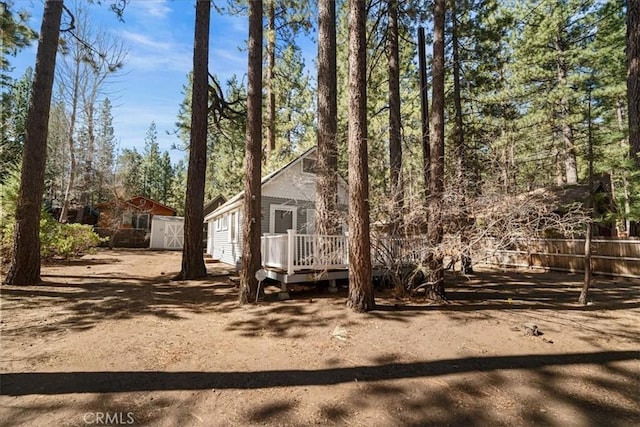 exterior space featuring an outdoor structure, a shed, a wooden deck, and fence