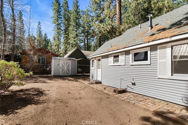 view of home's exterior with fence, a storage unit, and an outbuilding
