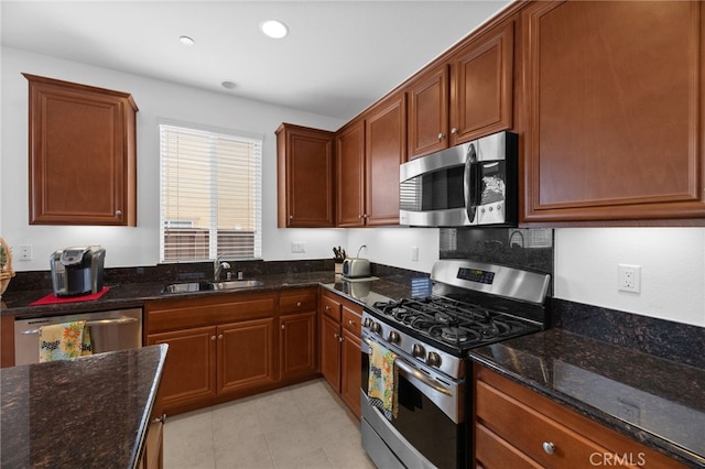 kitchen featuring dark stone counters, recessed lighting, a sink, and stainless steel appliances