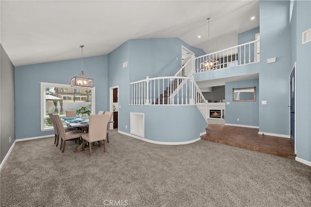 9334 Shamouti Dr, Riverside, CA 92508 - carpeted dining room featuring a chandelier, high vaulted ceiling, stairs, baseboards, and a warm lit fireplace