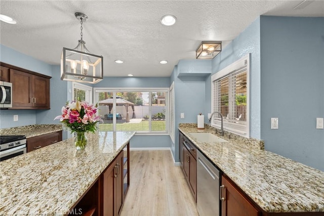 9334 Shamouti Dr, Riverside, CA 92508 - kitchen featuring a sink, appliances with stainless steel finishes, light wood finished floors, light stone countertops, and a textured ceiling