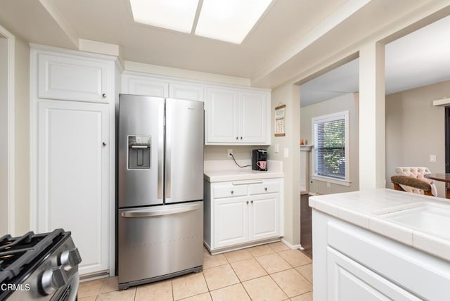 kitchen featuring stainless steel appliances, light tile patterned floors, white cabinets, a sink, and tile countertops