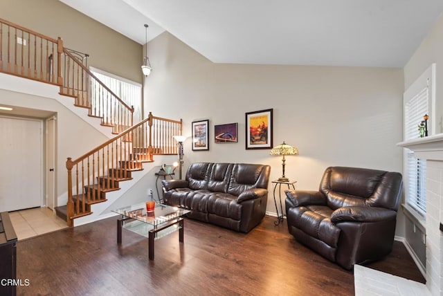 living area with baseboards, high vaulted ceiling, wood finished floors, and stairs