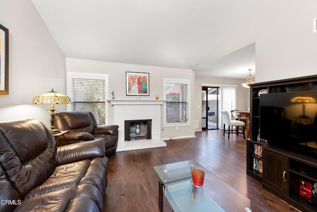 living room featuring a fireplace, dark wood-style floors, vaulted ceiling, and plenty of natural light
