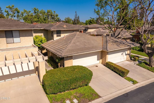 view of front of property with stucco siding, fence, concrete driveway, and a tiled roof