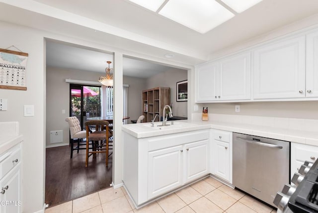 kitchen featuring light tile patterned floors, stainless steel dishwasher, white cabinets, a sink, and tile counters