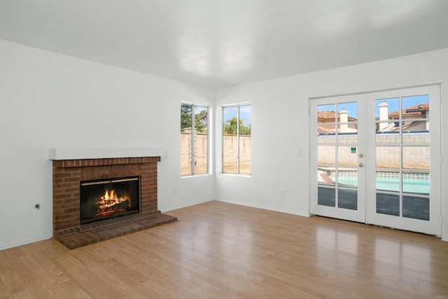 unfurnished living room featuring wood finished floors, baseboards, and a brick fireplace