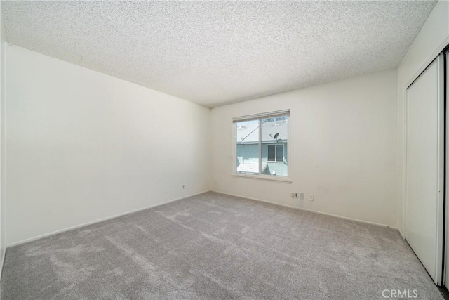 unfurnished room with baseboards, a textured ceiling, and carpet