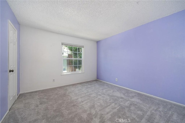 carpeted empty room with a textured ceiling and baseboards