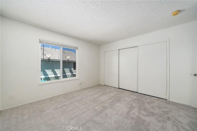 unfurnished bedroom featuring a textured ceiling, a closet, and carpet flooring