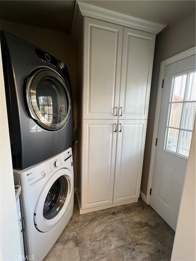 clothes washing area featuring cabinet space and stacked washer / drying machine