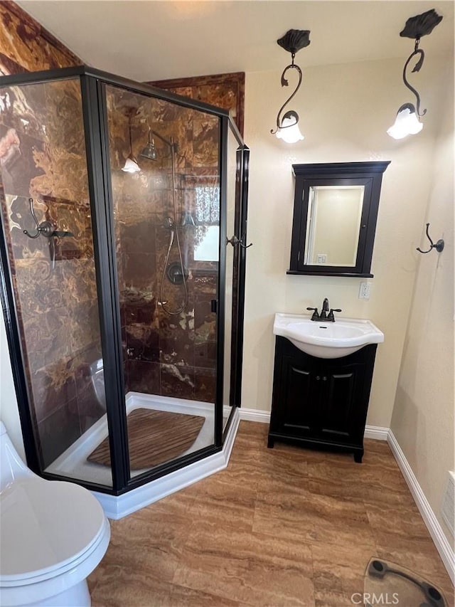 bathroom featuring vanity, a shower stall, wood finished floors, and baseboards