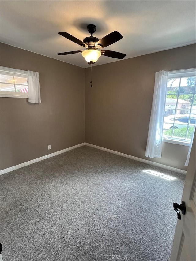 spare room with baseboards, ceiling fan, and carpet