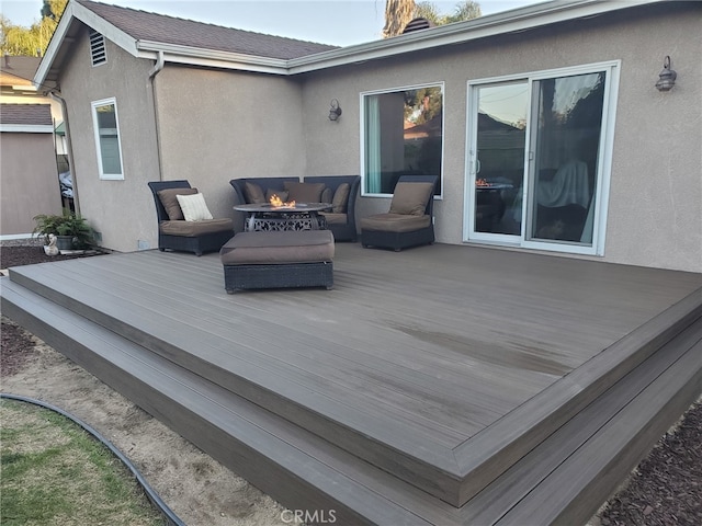 wooden deck featuring an outdoor living space with a fire pit