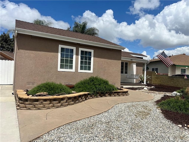 view of front of house with a patio, stucco siding, and fence