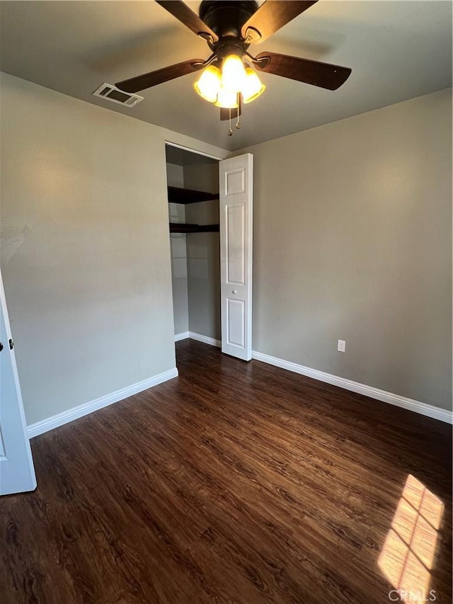 unfurnished bedroom with visible vents, a closet, dark wood-style floors, and baseboards