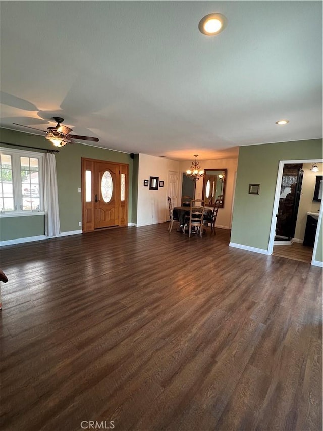 unfurnished living room featuring recessed lighting, ceiling fan with notable chandelier, dark wood finished floors, and baseboards