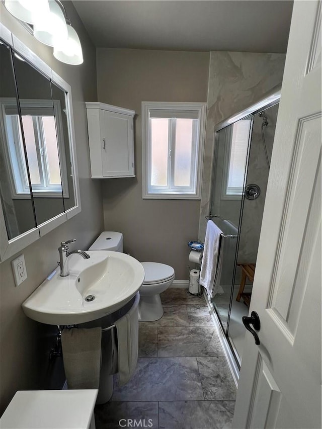 bathroom featuring toilet, a shower stall, and a sink