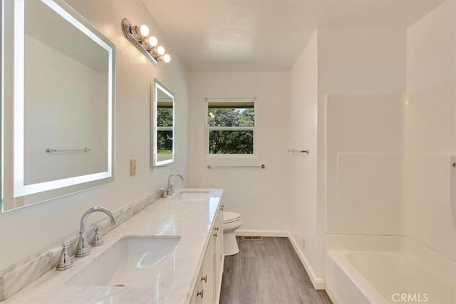 full bathroom featuring wood finished floors, toilet, double vanity, and a sink