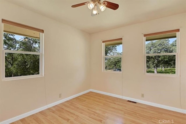 unfurnished room featuring baseboards, visible vents, a ceiling fan, and light wood-style flooring