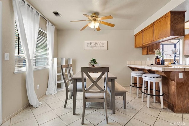 dining room featuring light tile patterned floors, visible vents, ceiling fan, and baseboards