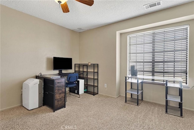 office area featuring a wealth of natural light, a ceiling fan, visible vents, a textured ceiling, and light colored carpet