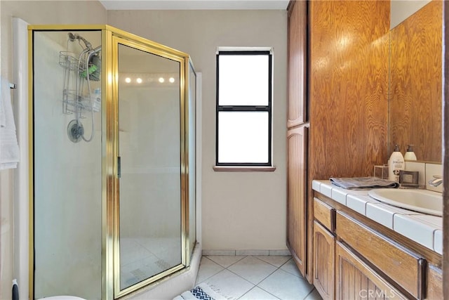 bathroom with tile patterned floors, baseboards, a stall shower, and vanity