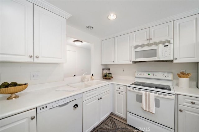 kitchen featuring white appliances, white cabinetry, a sink, and light countertops