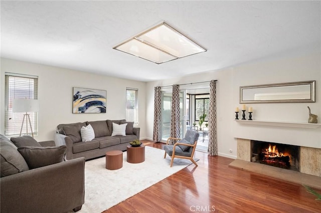 living room featuring a healthy amount of sunlight, a lit fireplace, and wood finished floors