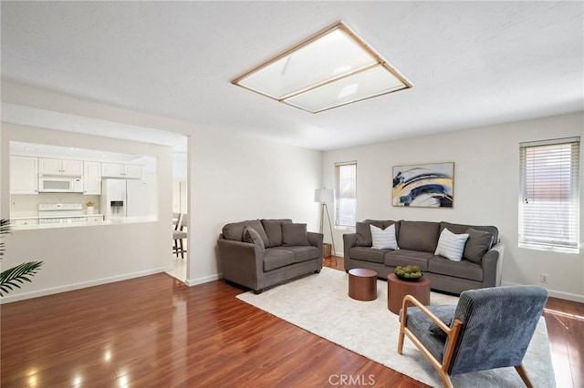 living area featuring baseboards, attic access, and dark wood-style flooring