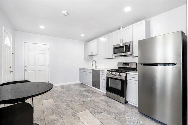 kitchen featuring recessed lighting, stainless steel appliances, light countertops, a sink, and baseboards