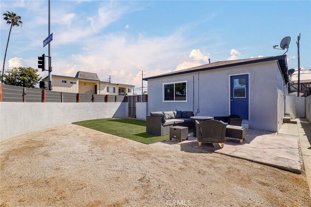 rear view of property with stucco siding, a patio, an outdoor hangout area, and a fenced backyard